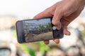 Hand holding a smartphone taking a photo of a couple of bicycles standing leaned on a wall