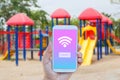 Hand holding smartphone with wifi connect on screen over outdoor play park blurred