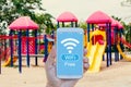 Hand holding smartphone with WiFi Free on screen over outdoor play park blurred