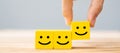 Hand holding smile face symbol on yellow wooden cube blocks. Emotion, Service rating, ranking, customer review, satisfaction and Royalty Free Stock Photo