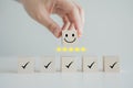 Hand holding smile happy face with 5 star and check mark on wooden block. Royalty Free Stock Photo