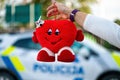 hand with a soft toy in the shape of a heart on a defocused background of a police car Royalty Free Stock Photo