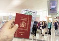 Hand holding a Spain passport with a wrinkled paper Coronavirus Covid 19 immunity certificate blurred airport in the background