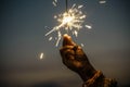 Hand holding sparkler firework firing with sunset sky in background - concept of new year eve celebration people - hope and love Royalty Free Stock Photo