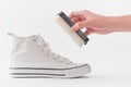 Hand holding a sponge against a white canvas sneaker Royalty Free Stock Photo