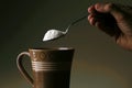 Hand holding a spoon with coffee creamer on it Royalty Free Stock Photo