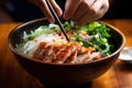 hand holding a spoon, scooping up a piece of grilled pork from a bun cha bowl Royalty Free Stock Photo