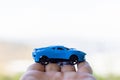 Hand holding sports blue toy car over