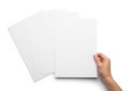A hand holding a stack of blank white paper sheets on a white background Royalty Free Stock Photo