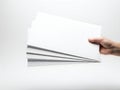 A hand holding a stack of blank white papers against a white background Royalty Free Stock Photo