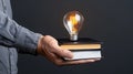 Hand Holding Stack of Books with Lightbulb Royalty Free Stock Photo