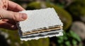 Hand holding stack of textured handmade paper sheets outdoors with blurred natural background light Royalty Free Stock Photo
