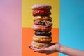hand holding a stack of various donuts, colorful background Royalty Free Stock Photo