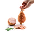 Hand holding a stick of boiled pork sausage. Sliced smoked ham, gammon with spices and fresh herbs isolated Royalty Free Stock Photo