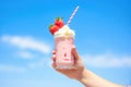 hand holding a strawberry shake against a blue sky background Royalty Free Stock Photo