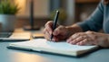 A hand holding a stylish black pen over an open notebook, minimalistic desk setup, blurred office background, warm ambient
