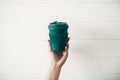 Hand holding stylish reusable eco coffee cup on white wooden background. Green Cup from natural bamboo fiber, zero waste concept Royalty Free Stock Photo