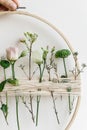 Hand holding stylish spring boho wreath with beautiful fresh flowers. Wooden hoop with flowers and thread. Modern and creative