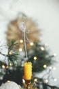 Hand holding stylish vintage candlestick with extinguish candle and smoke on background of warm lights, fir branches and sweden