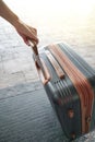 Hand holding suitcase in an airport. Woman with hand luggage in airport Royalty Free Stock Photo