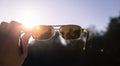 Hand holding sunglasses outdoors, blue sky, sunbeam and lens flares Royalty Free Stock Photo