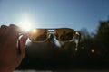 Hand holding sunglasses outdoors, blue sky, sunbeam and lens flares Royalty Free Stock Photo