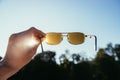 Hand holding sunglasses outdoors, blue sky, sunbeam and lens flares Royalty Free Stock Photo