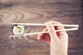 Hand holding sushi roll using chopsticks Royalty Free Stock Photo