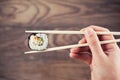 Hand holding sushi roll using chopsticks Royalty Free Stock Photo