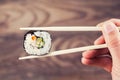 Hand holding sushi roll using chopsticks Royalty Free Stock Photo