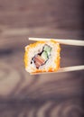 Hand holding sushi roll using chopsticks Royalty Free Stock Photo