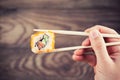 Hand holding sushi roll using chopsticks Royalty Free Stock Photo