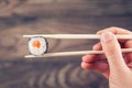 Hand holding sushi roll using chopsticks Royalty Free Stock Photo