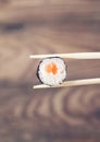 Hand holding sushi roll using chopsticks Royalty Free Stock Photo