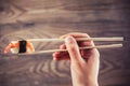 Hand holding sushi roll using chopsticks Royalty Free Stock Photo