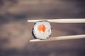 Hand holding sushi roll using chopsticks Royalty Free Stock Photo