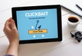 Hand holding tablet with clickbait concept on screen