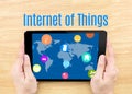 Hand holding tablet with Internet of things (IoT) word on wooden table Royalty Free Stock Photo
