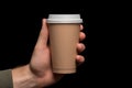 Hand holding takeaway paper coffee cup on a black background