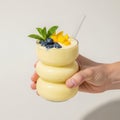 Hand holding a tall stack of three yellow donuts with fruit topping isolated on white background Royalty Free Stock Photo