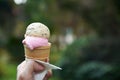 A hand holding a tasty melting ice cream cone