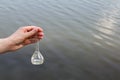 Hand holding test tube for analyses with water on the background of the reservoir, the concept of water purity, pollution of water Royalty Free Stock Photo