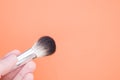 Hand holding a thick painting brush on orange background for a copy space Royalty Free Stock Photo