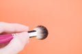 Hand holding a thick painting brush on orange background for a copy space Royalty Free Stock Photo