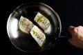 A hand holding three fish fillets with herbs and spices in a pan