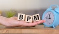 A hand holding three wooden blocks that spell out BPM. Royalty Free Stock Photo