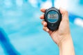 Hand holding a timer chronometer with a young man in the background at the swimming pool in Mexico Latin America Royalty Free Stock Photo