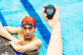 Hand holding a timer chronometer with a young man in the background at the swimming pool in Mexico Latin America Royalty Free Stock Photo