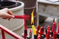 Hand holding to light the red incense with flame of candle in the temple Royalty Free Stock Photo