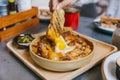 Hand holding toast dipping in Cheesy Breakfast Potatoes with Crispy Bacon and Fried egg